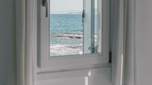 A room with a window overlooking a beach.