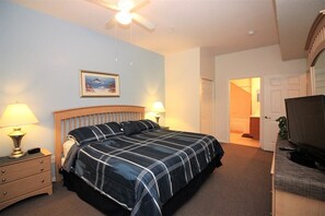 A hotel room with a bed, bedside lamps, a ceiling fan, a television, and a door leading to another room. - Venetian Bay Townhouse with Room for Ten - VB006 (Kissimmee)
