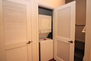 A laundry room with a washer and dryer, a door with a handle, and a small pink item on the dryer. - Venetian Bay Townhouse with Room for Ten - VB006 (Kissimmee)