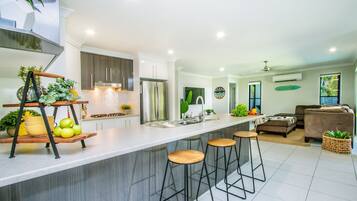 A modern kitchen with a central island, bar stools, and a dining area with a sofa and coffee table.