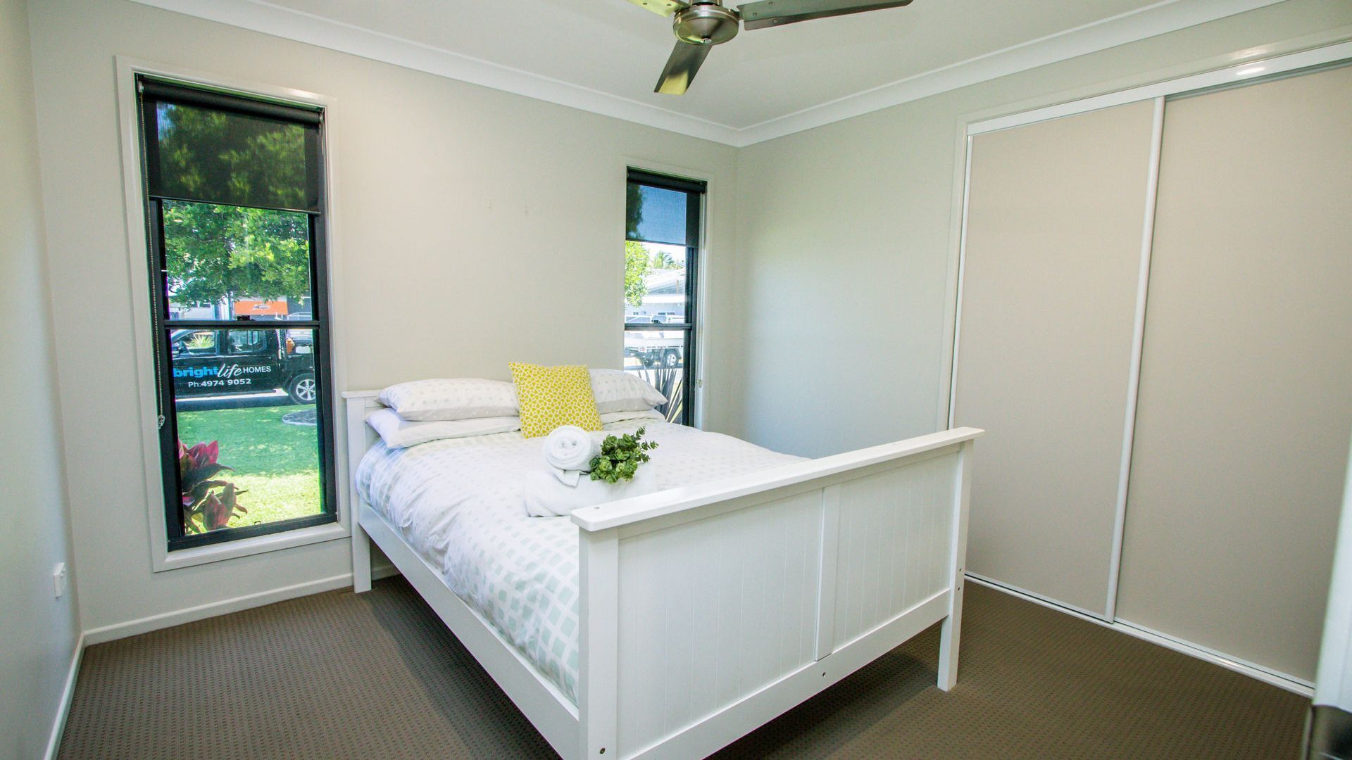 A bedroom with a bed, a window, a ceiling fan, and a wardrobe.