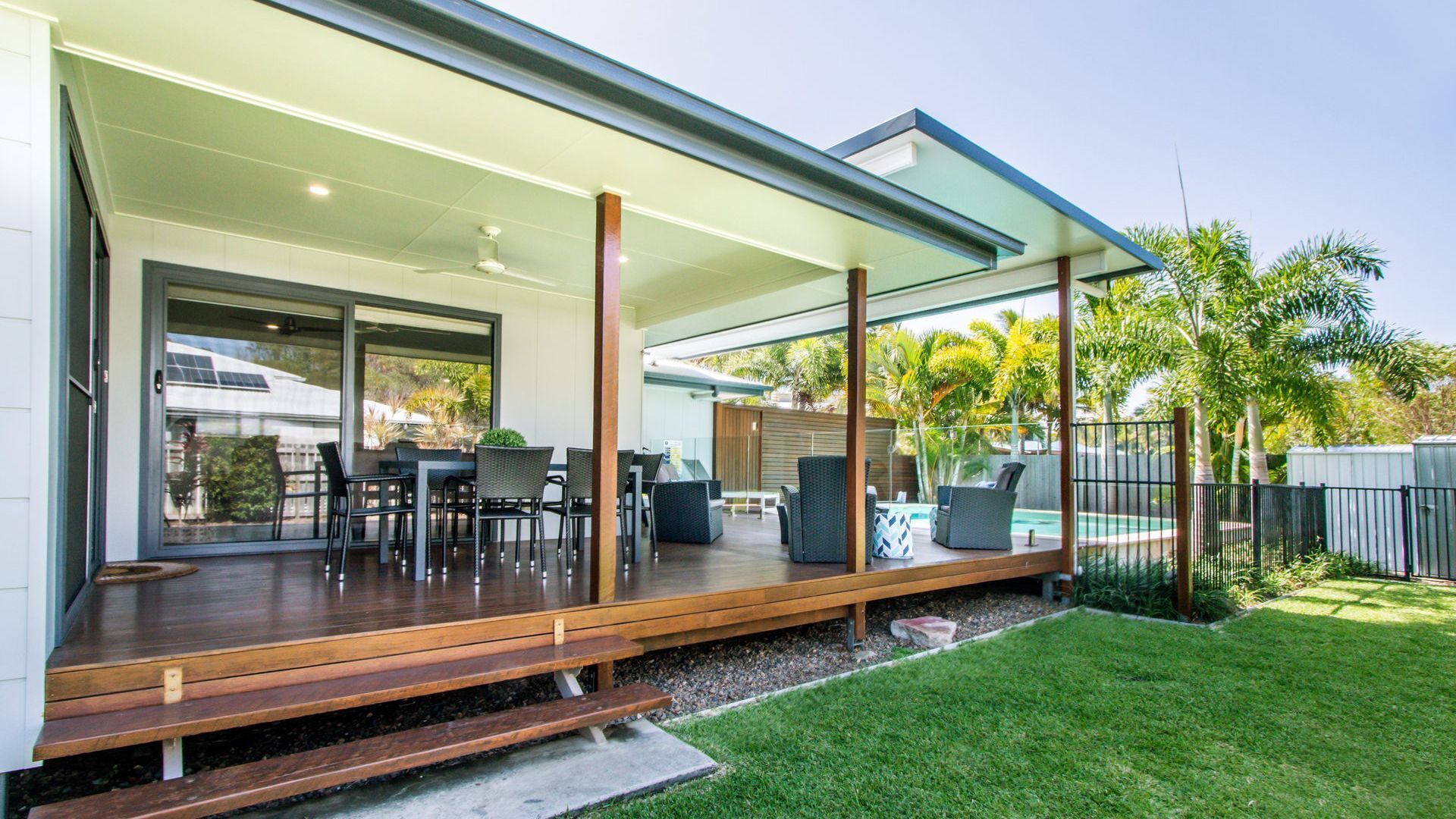 Un patio couvert avec des meubles d’extérieur, une piscine et une pelouse bien entretenue.
