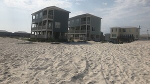 Ein Gebäude direkt am Strand mit mehreren Balkonen und einem sandigen Strand im Vordergrund.