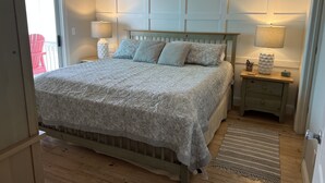 Ein Schlafzimmer mit einem Bett, Nachttischen, einer Lampe und einem Holzboden.