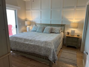 A bedroom with a bed, nightstands, a lamp, and a wooden floor. - Beautiful 5 bed/4 bath home with breathtaking views and steps from the water! (Gulf Shores)