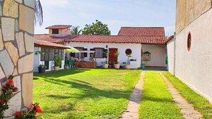 Un patio con tejado de tejas rojas, pared de piedra y camino empedrado.