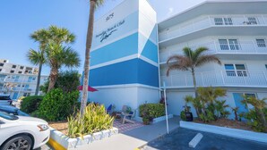 Ein mehrstöckiges Hotel mit Balkonen, Palmen und einem Schild, das anzeigt, dass es sich um den Paradise Beach Club handelt.