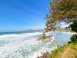 A coastal landscape with a clear view of the ocean, waves, and a distant mountain.