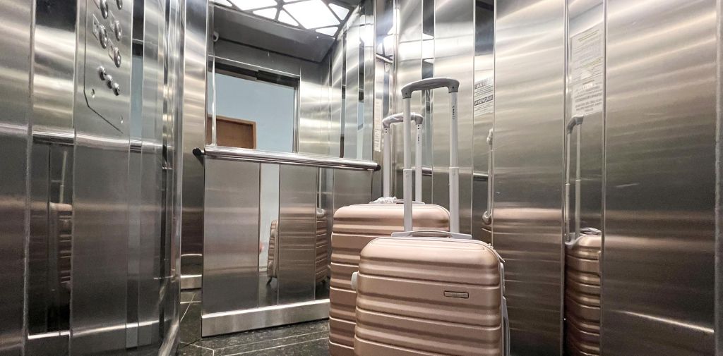 Un ascensor con capacidad para 8 personas, con paredes de acero inoxidable y pasamanos.