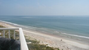 Vista sulla spiaggia dal balcone, con cielo sereno, spiaggia sabbiosa e mare calmo.