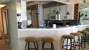 Una cucina moderna con isola centrale, sgabelli da bar e illuminazione a sospensione.