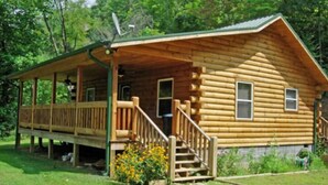A log cabin with a porch, a staircase leading to the entrance, and a small garden area with yellow flowers.