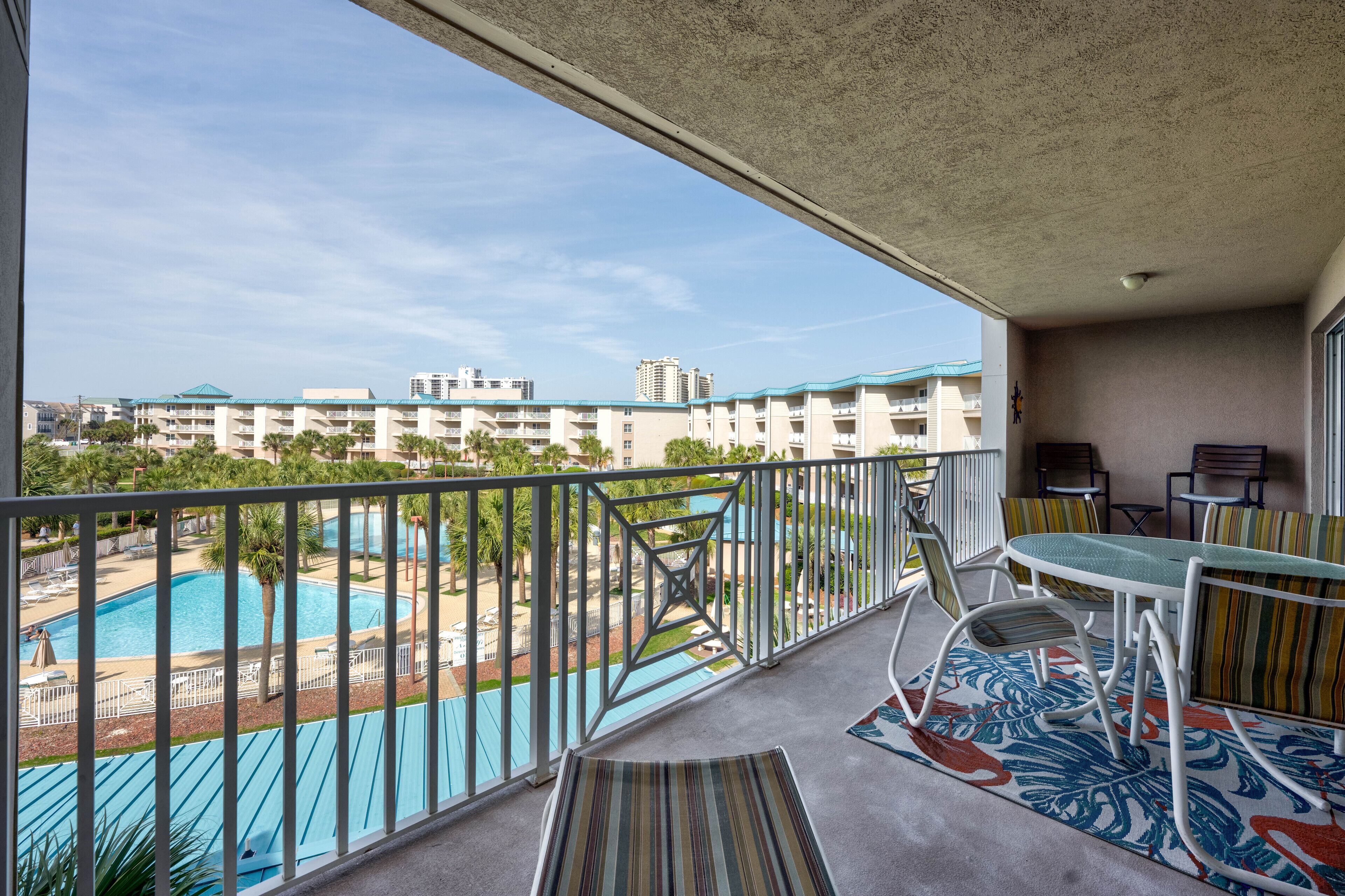 A balcony with a pool view, outdoor furniture, and a view of a residential area.