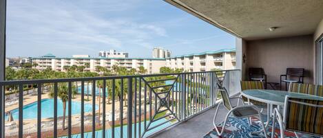 A balcony with a pool view, outdoor furniture, and a view of a residential area.