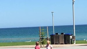 Zwei Kinder spielen auf einem Basketballplatz mit Blick auf den Ozean.