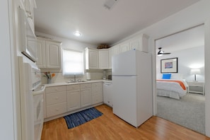 A compact kitchen with white cabinets, a refrigerator, and a blue rug.