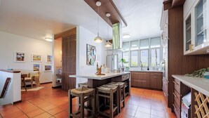 A modern kitchen with a central island, wooden bar stools, and a dining area with a chair. - Best Spot in Puerto Rico at Rio Mar Beach  & Golf Resort 20 min. to San Juan (Río Grande)