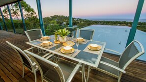 A dining table set for six with a view of the ocean.