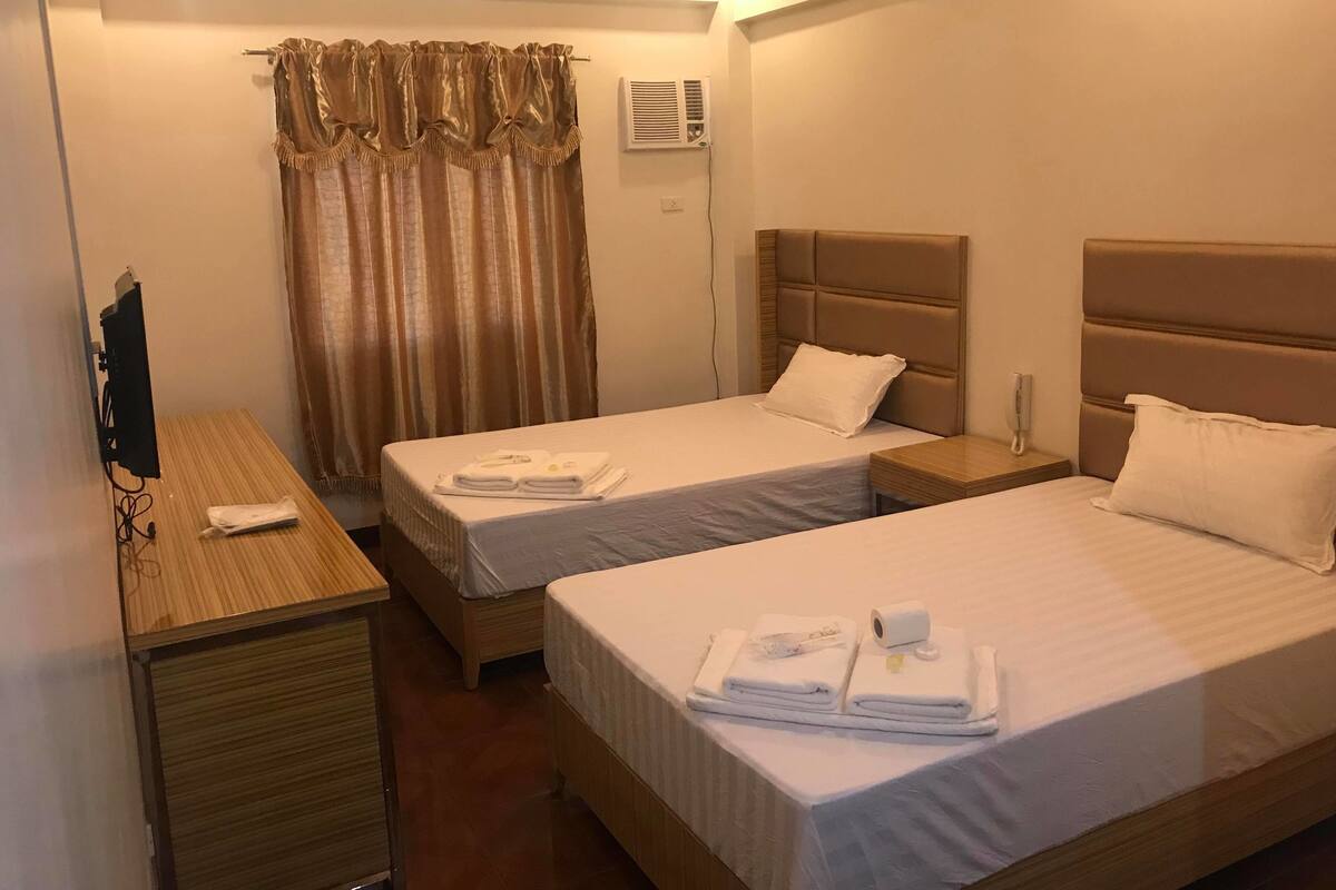Une chambre d’hôtel avec deux lits, un bureau et une télévision.