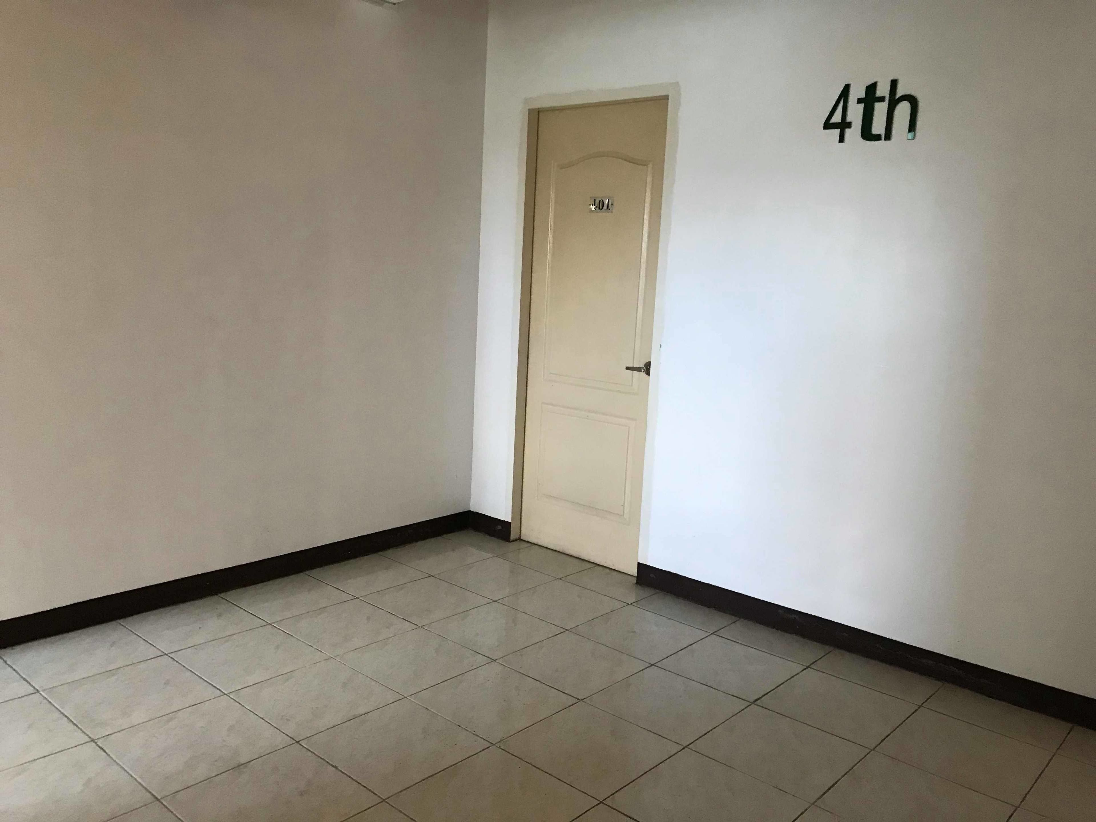 Un couloir doté d’un sol carrelé et d’une porte portant l’inscription « 4e ».