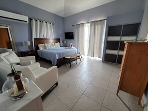 A bedroom with a bed, a desk, a chair, a TV, and a wardrobe. - BACK TO BUSINESS 
Golf Cart,Swimming Pool, generator & Breathless Scenic Views! (Humacao)
