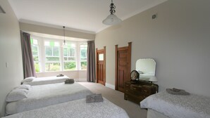 A bedroom with two single beds, a dresser, and a window with curtains.