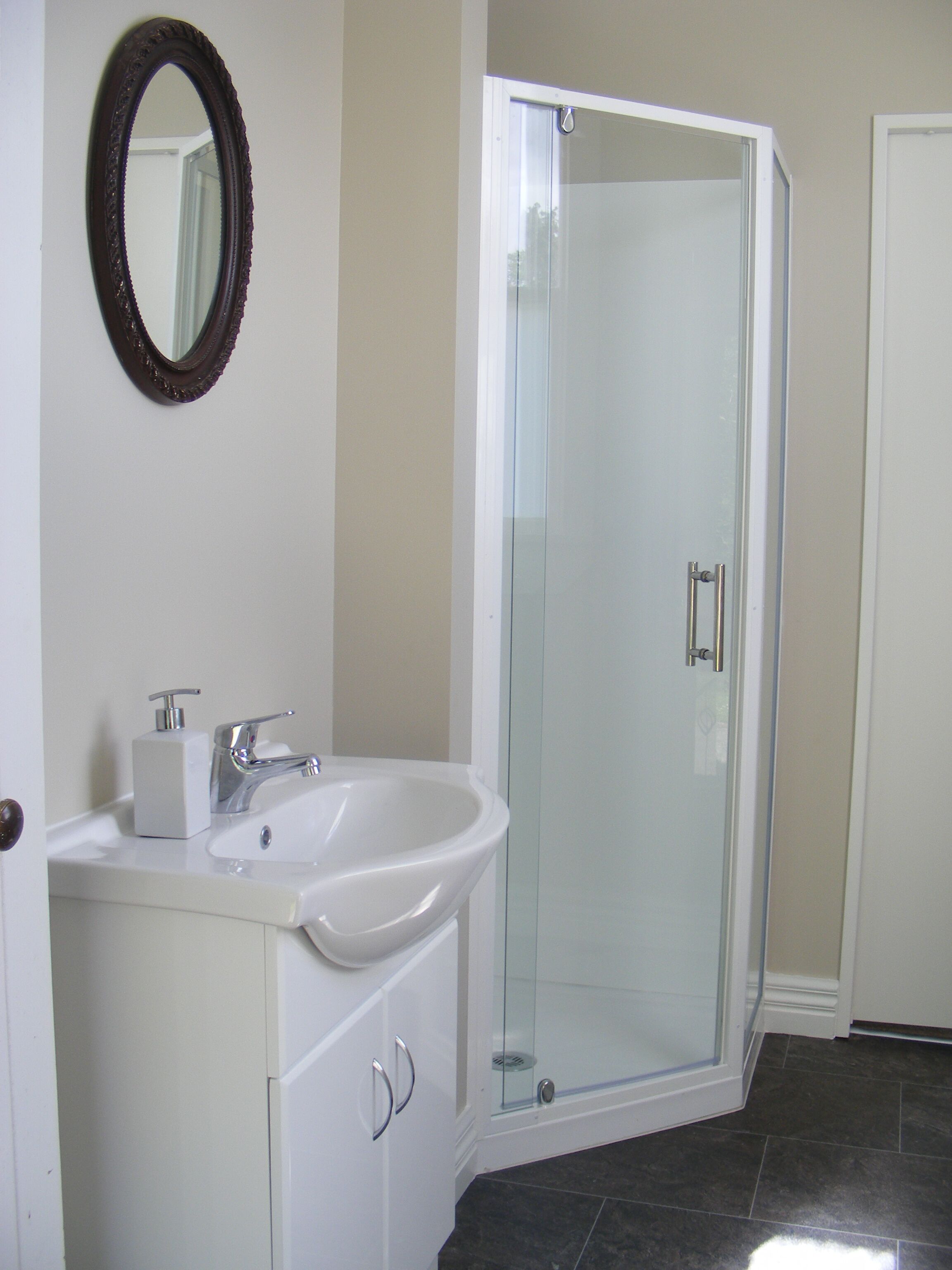 A bathroom with a white sink, a mirror, and a glass shower enclosure.