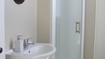A bathroom with a white sink, a mirror, and a glass shower enclosure.