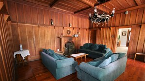 A cozy living room with wooden paneling, a fireplace, and a large sectional sofa.