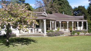 A two-story house with a porch, surrounded by a well-maintained lawn and flowering trees.