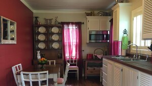 A kitchen with a dining table, chairs, a microwave, and a sink. - Peaceful, Private Cottage On Bayou Teche (New Iberia)