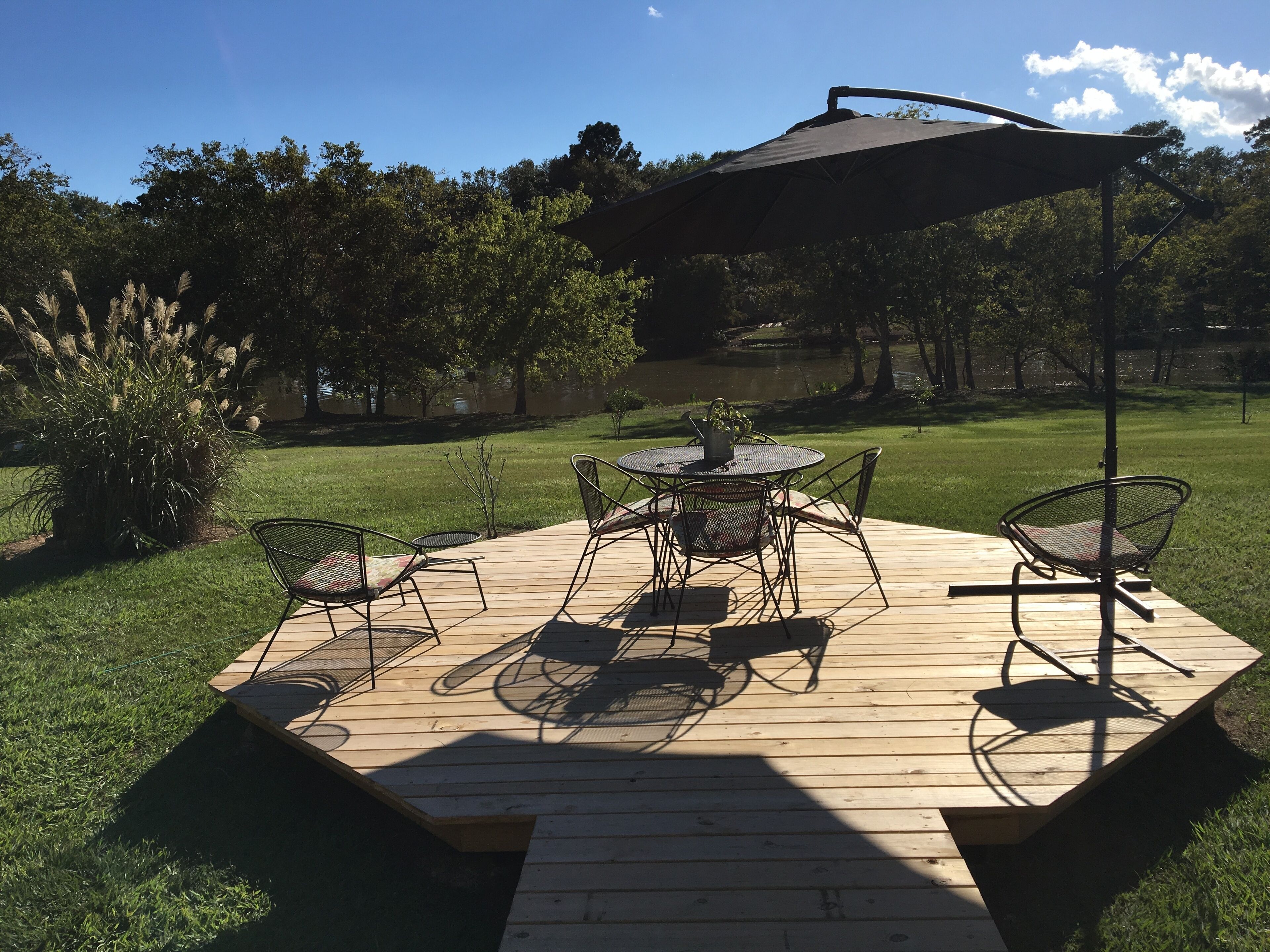 Eine Terrasse im Freien mit einem runden Tisch und Stühlen, umgeben von einer Holzterrasse.