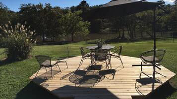 Eine Terrasse im Freien mit einem runden Tisch und Stühlen, umgeben von einer Holzterrasse.