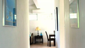 A hallway with a tiled floor, a table with chairs, and framed pictures on the walls. - Sea Breeze - FABULOUS NORTH SHORE (Vieques)