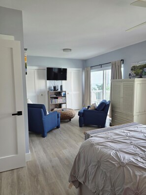 Ein Schlafzimmer mit einem Bett, zwei blauen Sofas, einem Bücherregal und einem Fernseher.