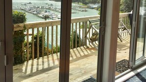 Un balcon avec vue sur une marina et sur des collines.
