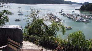 Un port de plaisance où sont amarrés de nombreux bateaux, entouré d’une végétation luxuriante et avec des collines en arrière-plan.
