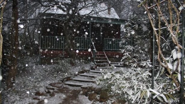 A snow-covered outdoor staircase leading to a building with a balcony.
