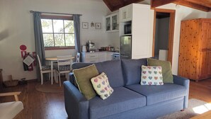 A living room with a sofa, a dining table, and a kitchen in the background.
