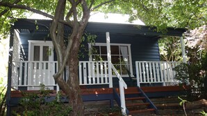 A house with a porch, wooden steps, and a tree in front.