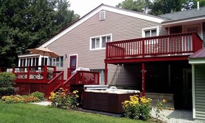 A two-story house with a red balcony, a covered porch, and a hot tub in the front yard. - Perfect Location with Jacuzzi! 10 min. to Storyland, 15 min. to Outlet shopping. (Intervale)