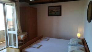 Quarto com cama, guarda-roupa, porta de vidro deslizante e um quadro na parede.