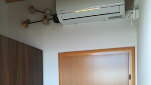 Um quarto com porta de madeira, unidade de ar condicionado no teto e guarda-roupa de madeira.