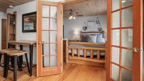 A cozy bedroom with a wooden bed, a desk with stools, and a ceiling fan. - Ski In/Out, Walk to Shops, Steam Shower in Unit + Outdoor Hot Tub (Steamboat Springs)