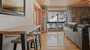 A cozy room with a wooden table, chairs, a sofa, and a stone wall. - Ski In/Out, Walk to Shops, Steam Shower in Unit + Outdoor Hot Tub (Steamboat Springs)