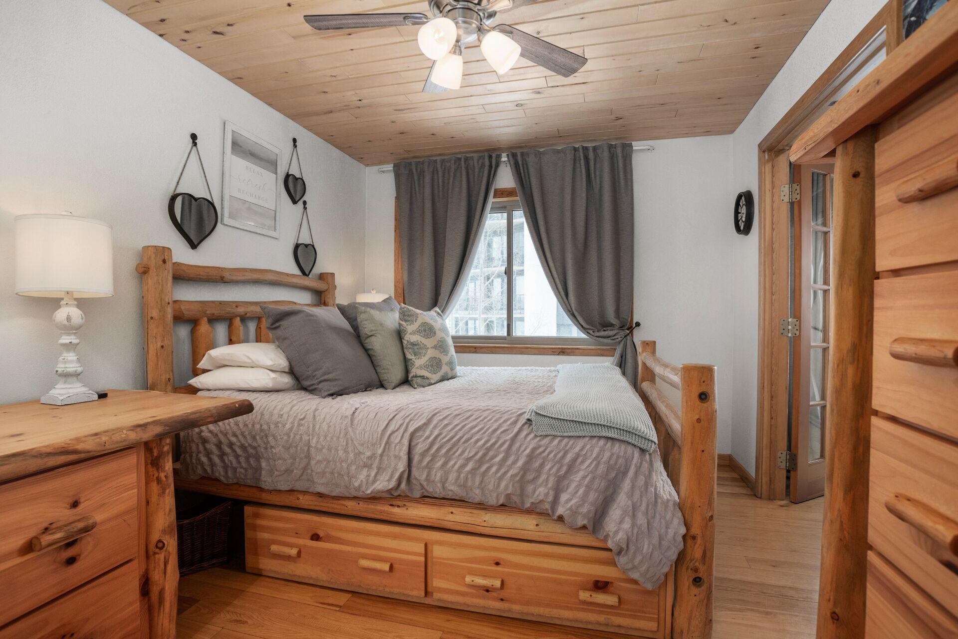 Un dormitorio acogedor con una cama de madera, una mesita de noche, una lámpara y un ventilador de techo.