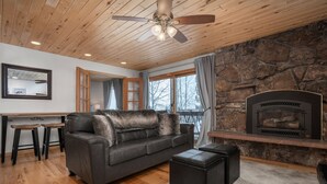 A cozy living room with a stone fireplace, leather sofa, and ottomans. - Ski In/Out, Walk to Shops, Steam Shower in Unit + Outdoor Hot Tub (Steamboat Springs)