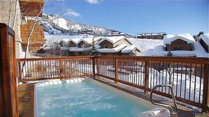 A hot tub on a wooden deck with a view of snow-covered houses and a mountain in the background. - Ski In/Out, Walk to Shops, Steam Shower in Unit + Outdoor Hot Tub (Steamboat Springs)