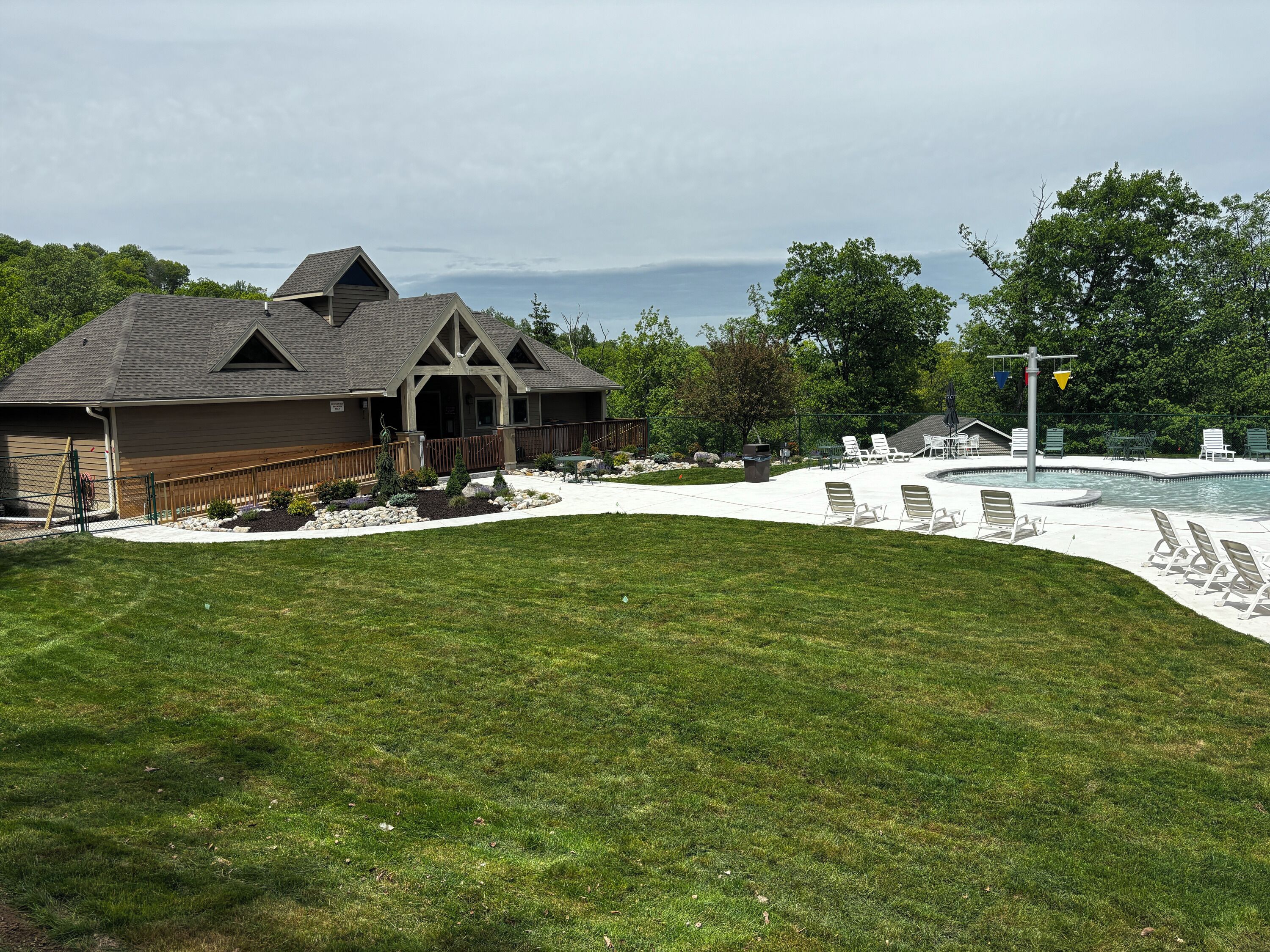 A residential property with a swimming pool, outdoor seating, and a well-maintained lawn.