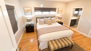 Une chambre à coucher avec un grand lit, des tables de chevet, un banc et un miroir.